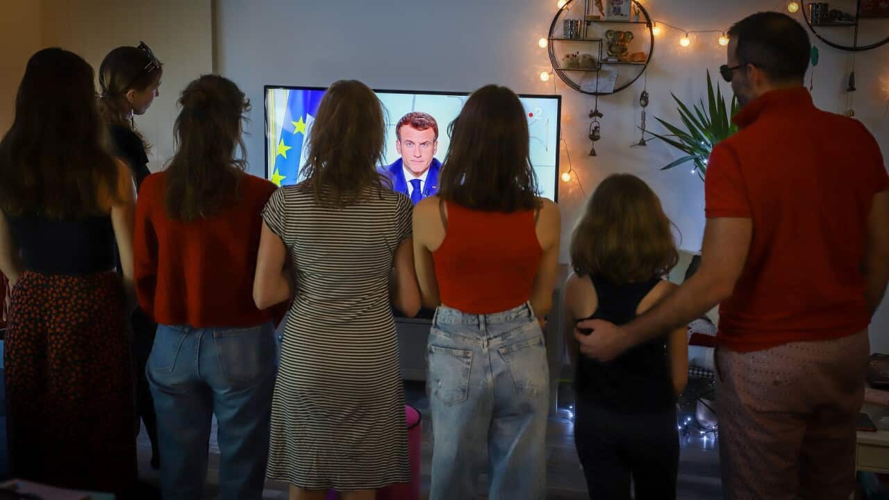 A family watches French President Emmanuel Macron as he announces new restrictions