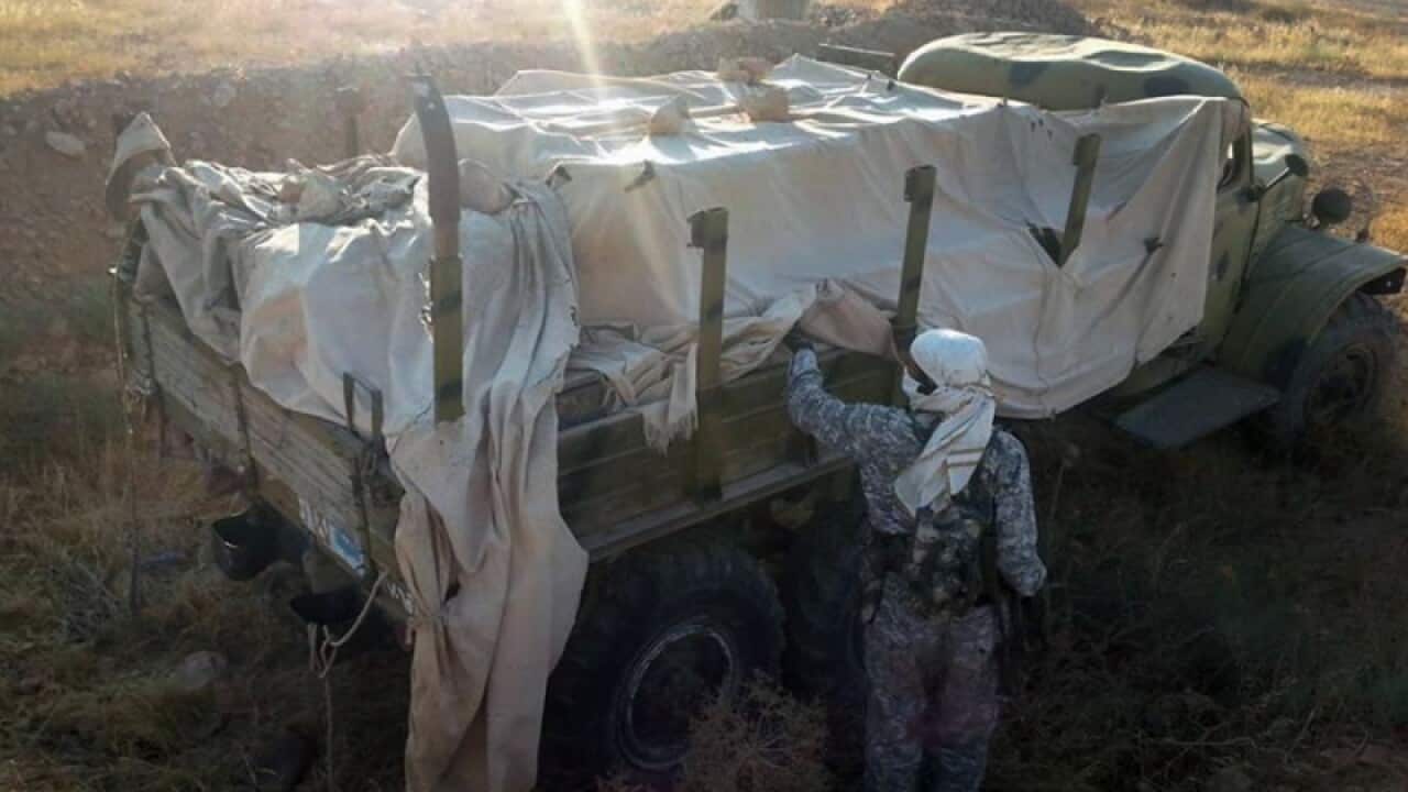 An Islamic State fighter inspects a military truck