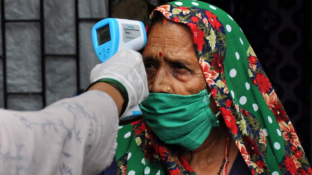 A healthcare worker checks the temperature of a woman at Sathe Nagar, a slum in Mumbai.
