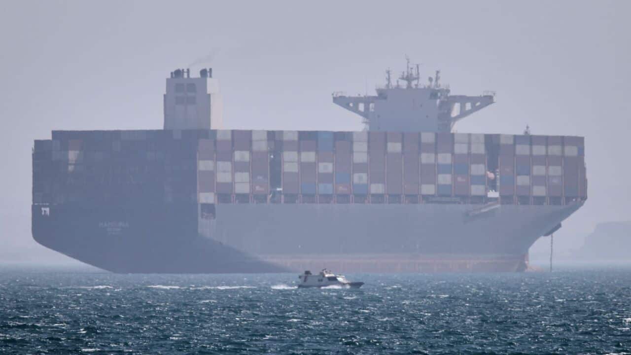 A container ship sits at anchor as a small motorboat passes in the foreground in the Strait of Hormuz off Bandar Abbas, Iran, Saturday, May 2, 2026. (Amirhosein Khorgooi-ISNA via AP).jpg