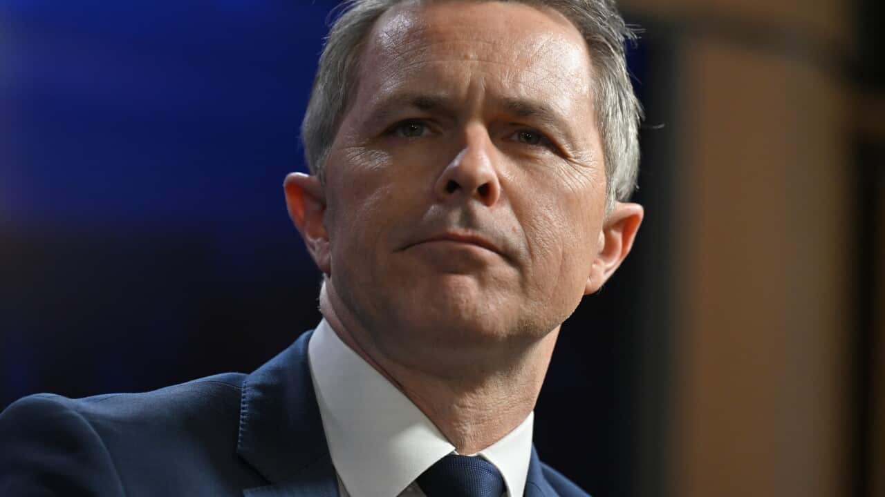 A man wearing a suit and tie standing at a podium.