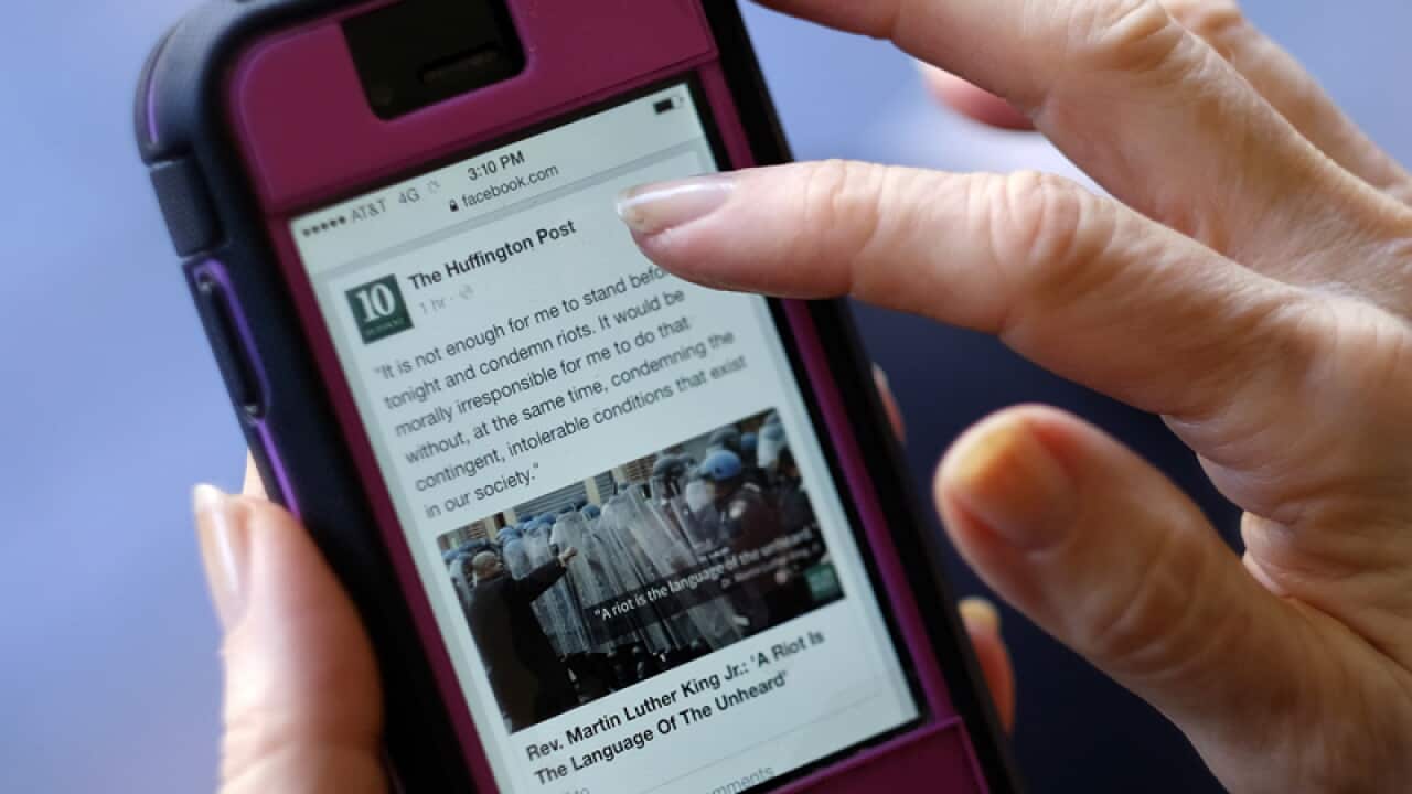 A person uses a mobile phone to read the news on Facebook