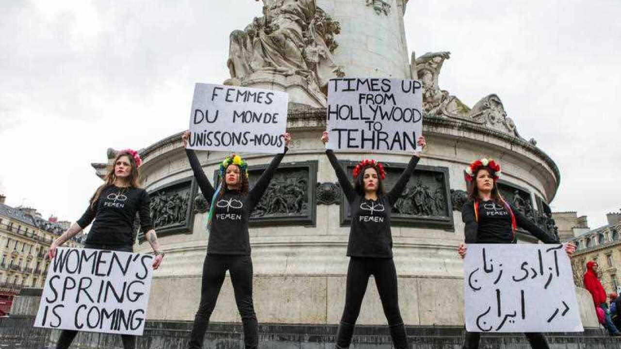 Women hold signs on the streets of Paris as part of a nationwide strike on International Women's Day on March 8, 2018.