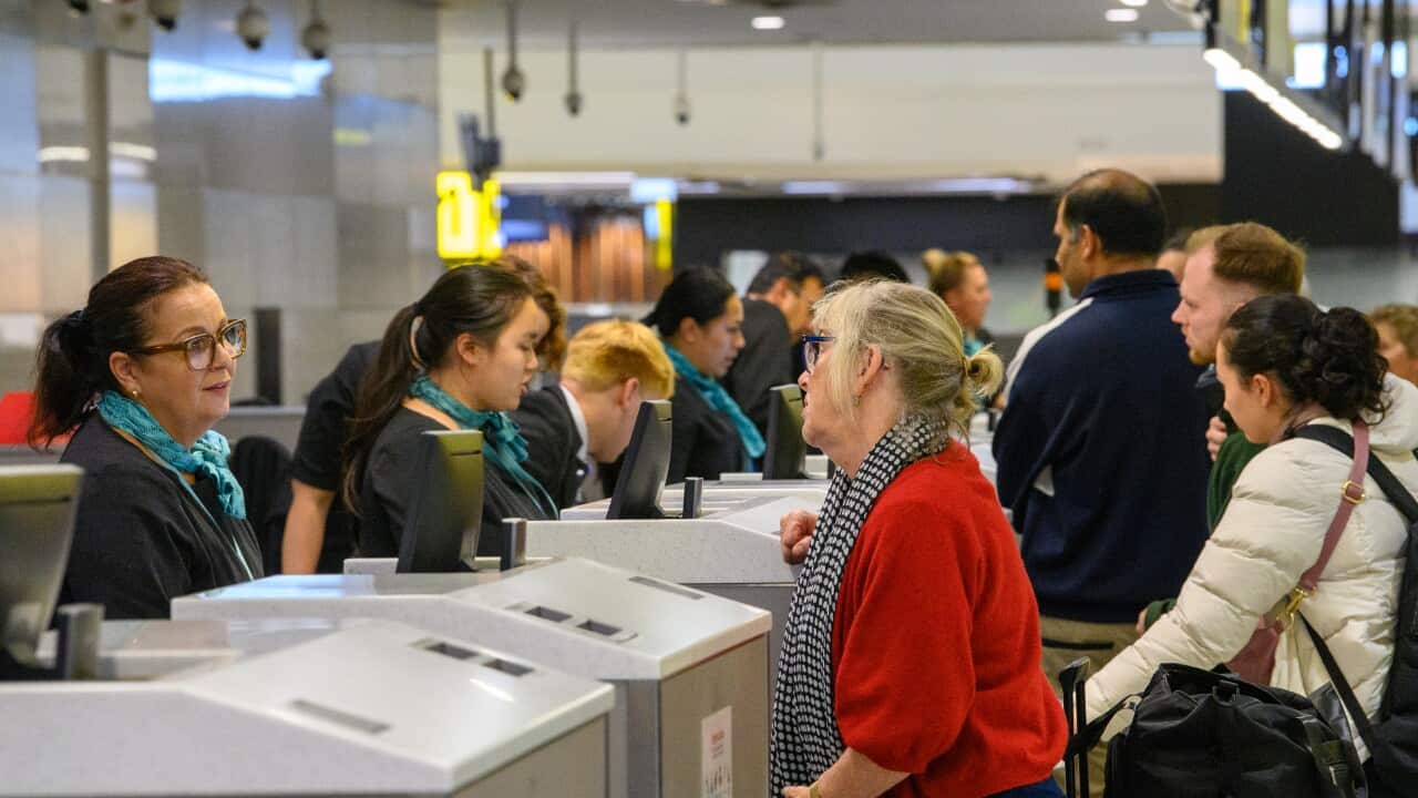 Passengers at an airport queuing to check in for a flight.