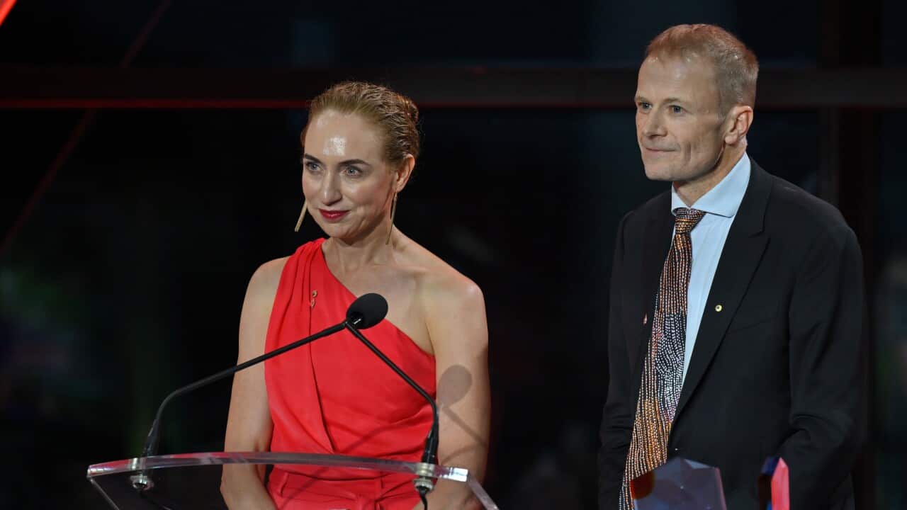 A woman and a man speaking on stage.