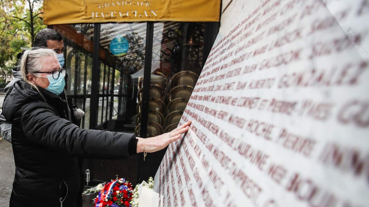 A woman touches the memorial stone after she put flowers outside the Bataclan concert venue, a site of the terror attacks, in Paris, France, 13 November 2020.