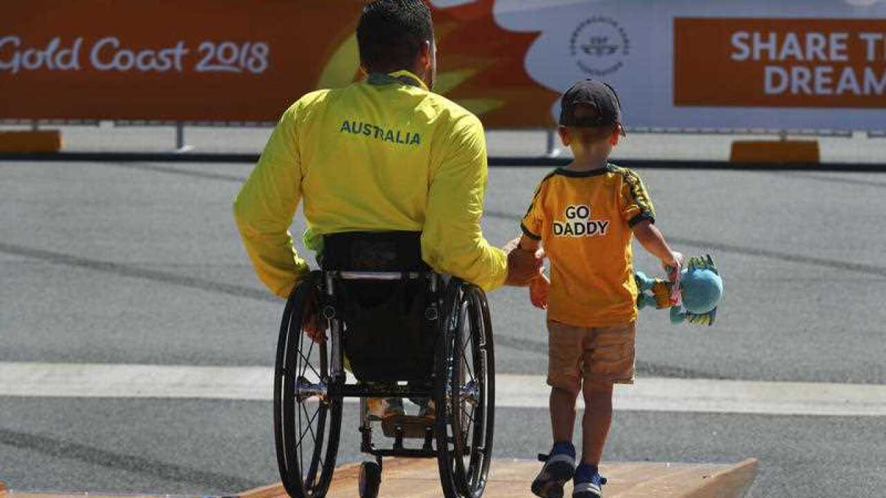 Kurt Fearnley leaves with his son Harry after a medal ceremony at the Commonwealth Games.