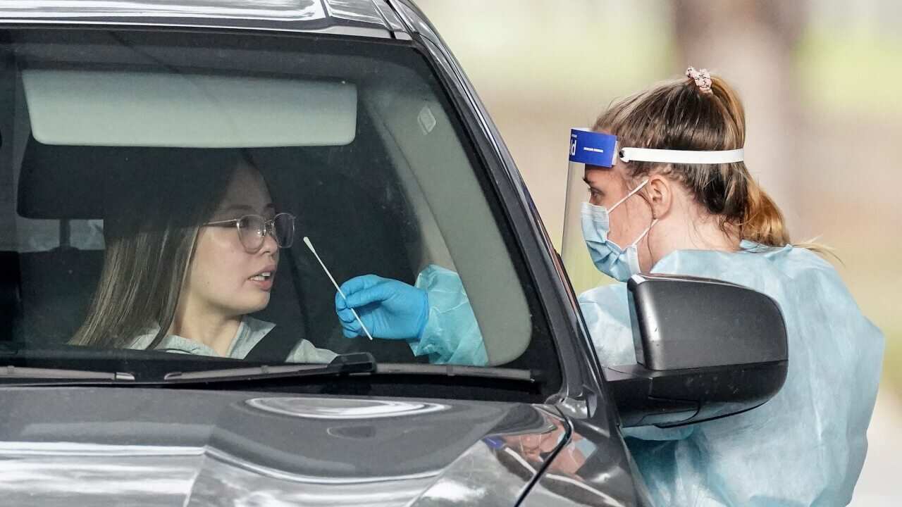 A medical worker takes a sample from a person at a drive-through COVID-19 pop-up testing clinic at the Keilor Community Hub in Melbourne