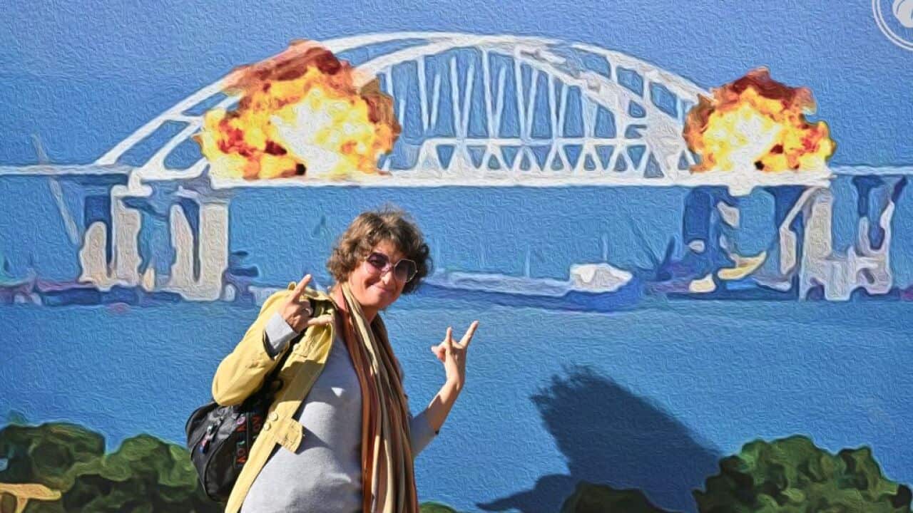 A woman poses in front of an artwork shaped as a big stamp entitled (with a play on words) "Cotton to the Crimean Bridge" created by Andrusiv V, Serdyukov O, Kalinovska Y, Visich M depicting today's explosion on Kerch bridge, set in the centre of Ukrainian capital of Kyiv.
