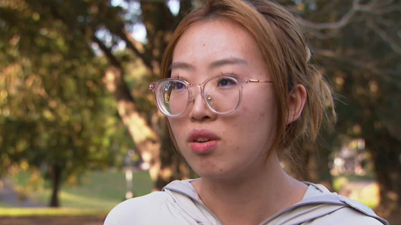 A close up of a woman wearing glasses who is speaking while standing outside.