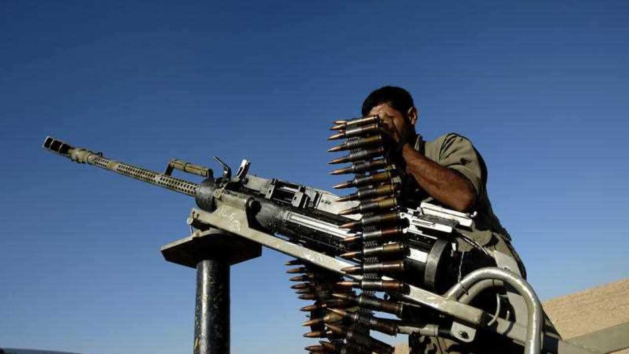 A member of the Kurdistan Workers Party (PKK) inspects his weapon while helping patrol the outskirts of Makhmur, a northern Iraqi town near Erbil