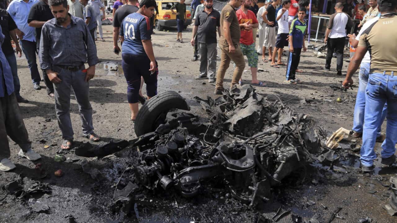 Citizens inspect the scene after a suicide car bombing