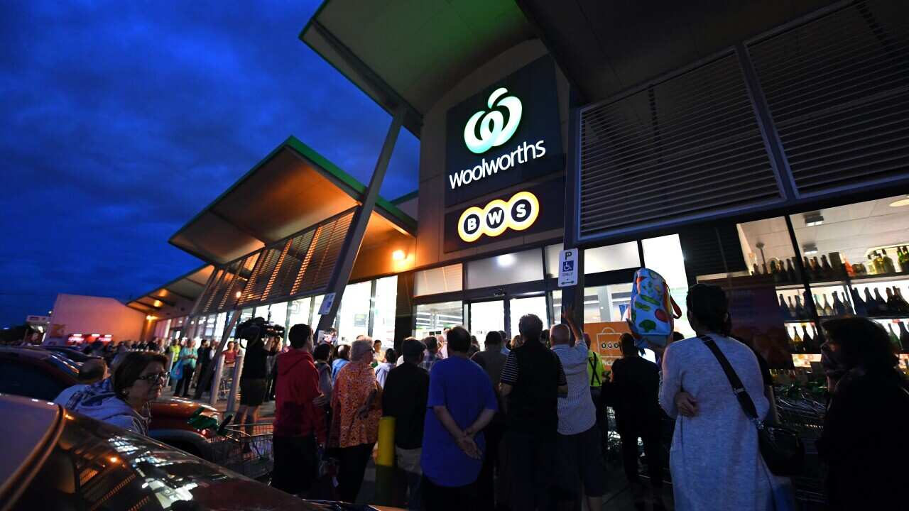 People are seen waiting outside a Woolworths supermarket in Melbourne
