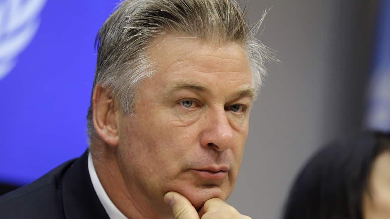 Alec Baldwin scratches his chin as he contemplates something.