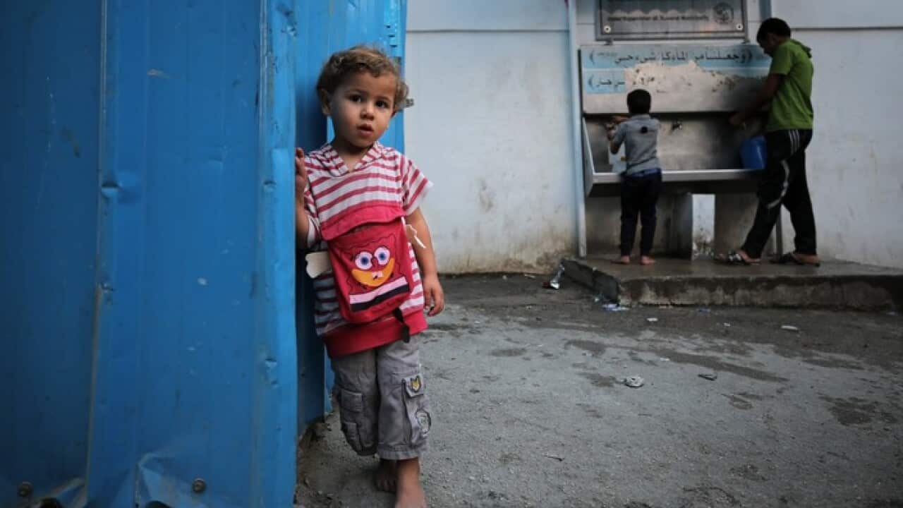 Palestinian refugee boys fill containers with drinking water from public taps during Ramadan, in the Gaza Strip
