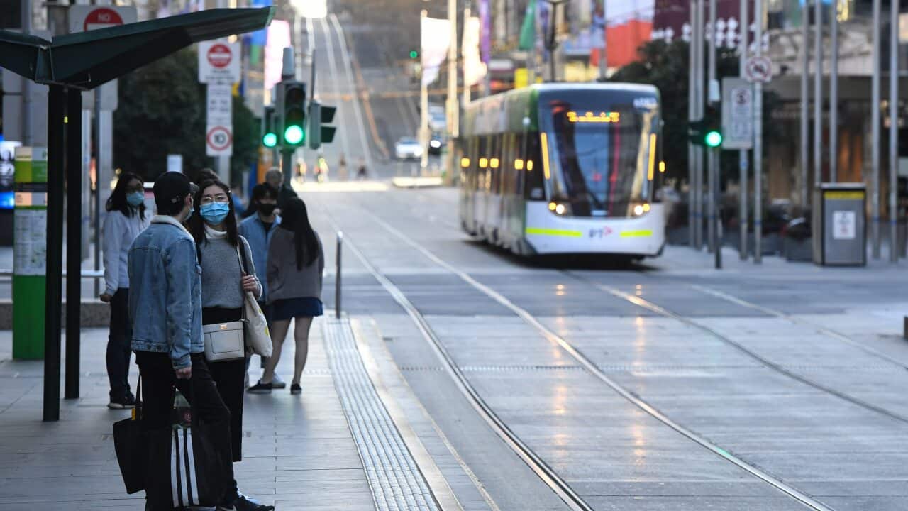 People wait for a tram on Bourke Street in Melbourne, Sunday, 6 September, 2020.