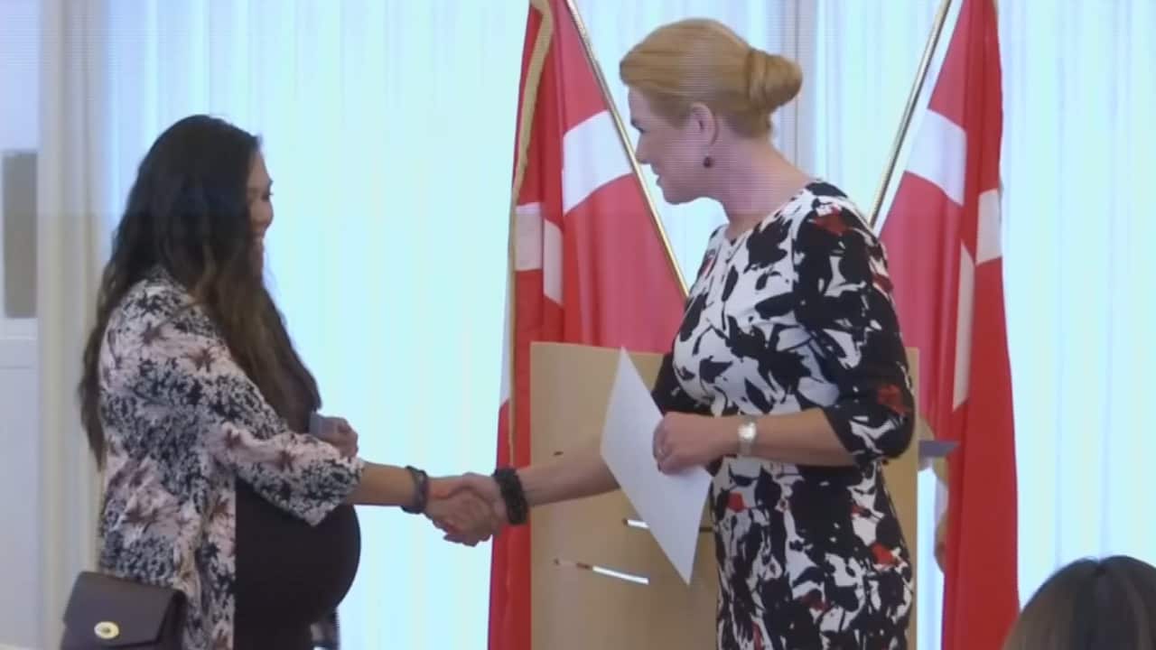 New Danish citizen, Sheryll Dufke, walking up to Stojberg and receiving her proof of citizenship. 