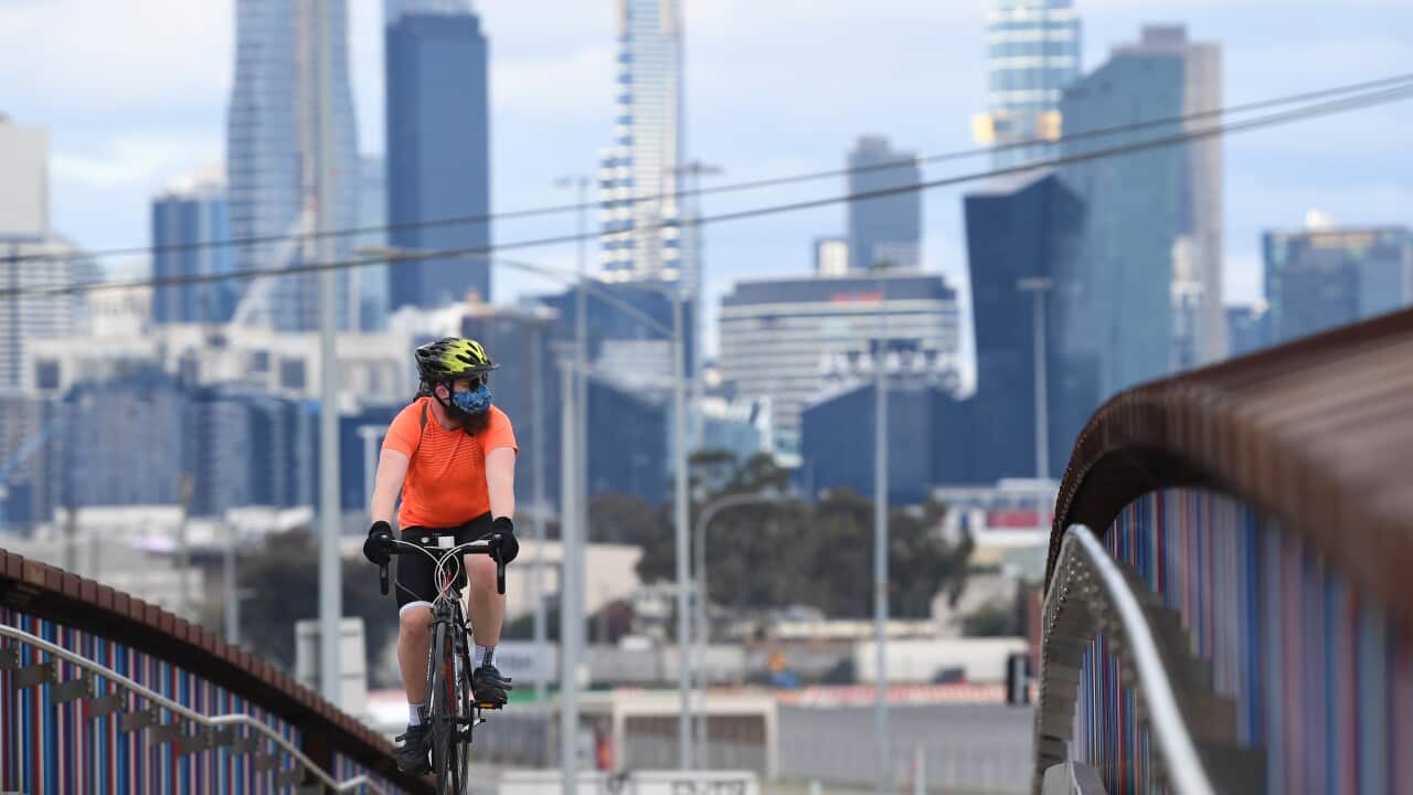 A cyclist wearing a face covering crosses an overpass in Melbourne.