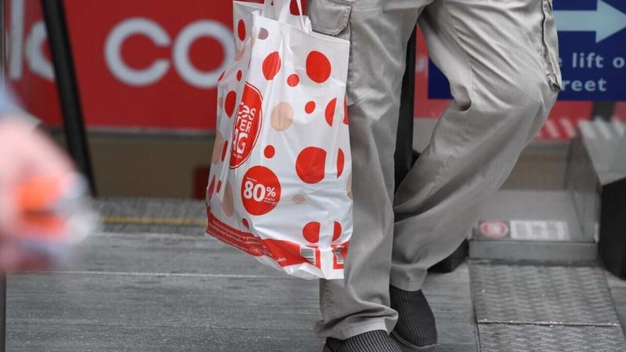 A shopper is seen carrying a reusable plastic bag at a Coles.