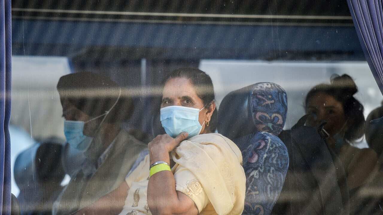 Travellers returning from India onboard a waiting bus to begin their 14-day imposed quarantine.