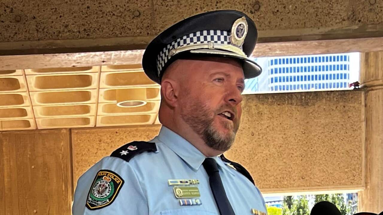 A police officer in uniform speaking into microphones.