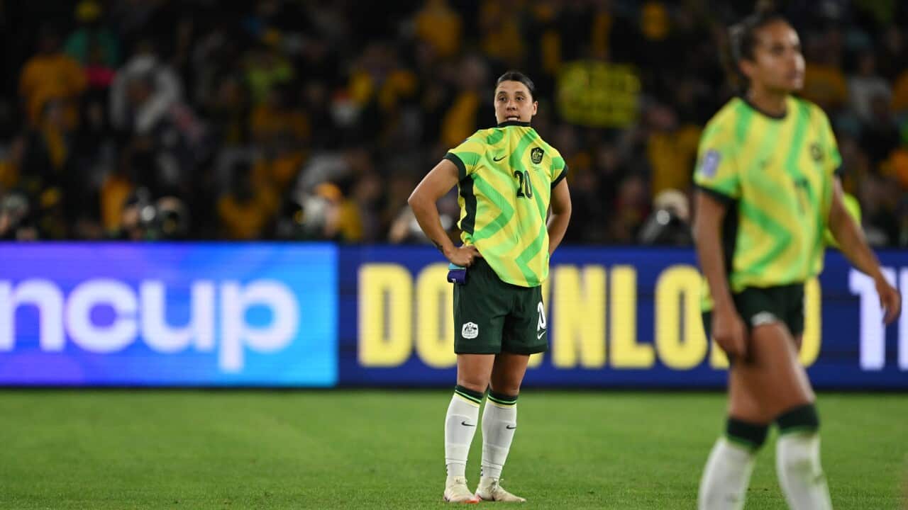Two football players stand on the pitch wearing yellow and green jerseys