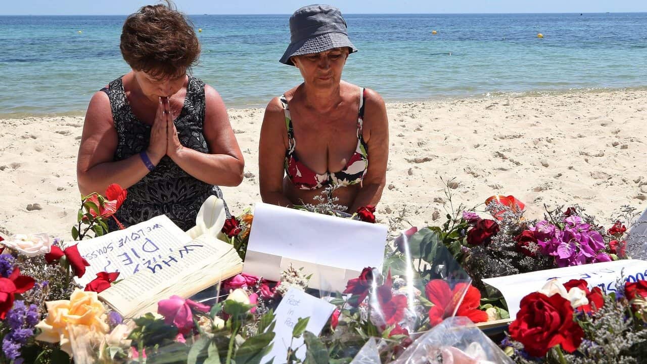 A Tourist prays beside flowers placed in tribute to the people killed in a terror attack on a beach in front of the imperial Marhaba Hotel in Sousse,Tunisia.