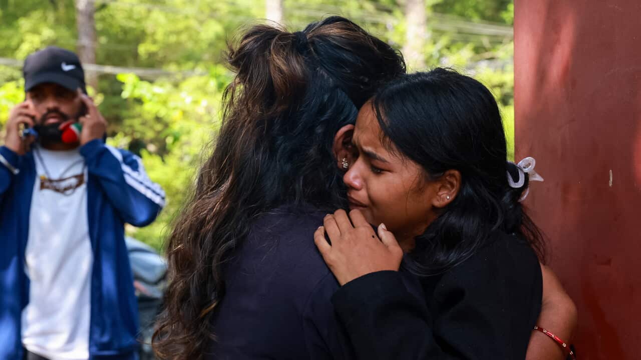 A woman cries on the shoulder of another woman who is trying to console her