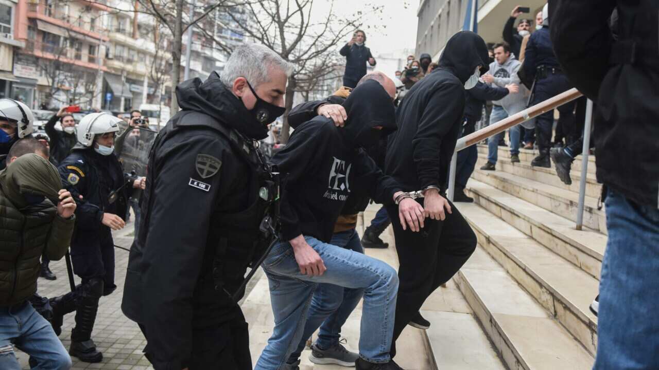 Police officers in escort three men to the courthouse in the northern port city of Thessaloniki , Greece, on Monday, Feb. 7, 2022.