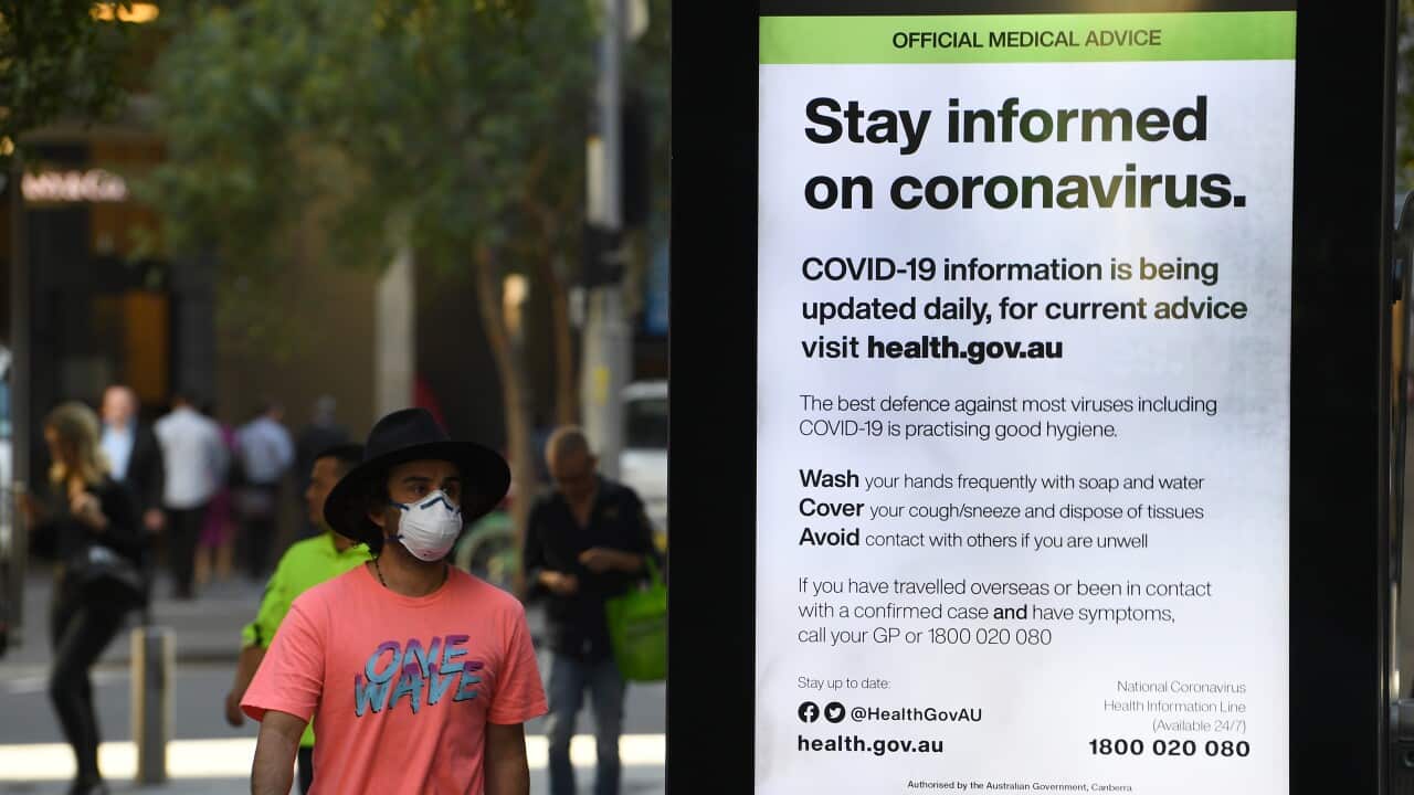 A man wearing a protective mask walks past an official medical advice advertisement in Sydney's Pitt Street Mall.