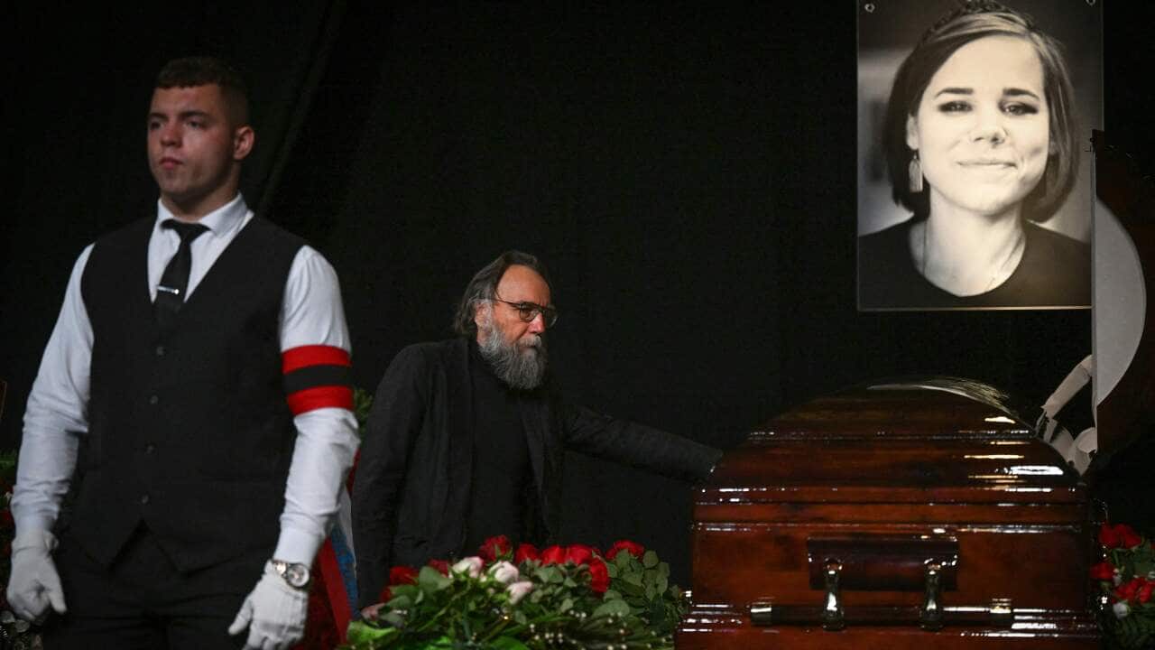Daria Dugina's father stands next to her coffin at her funeral.