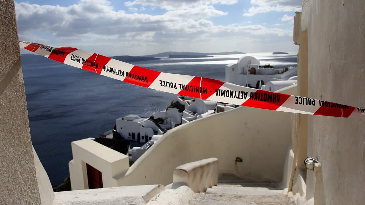 A red warning ribbon blocks a narrow white passage, warning of earthquake activity.