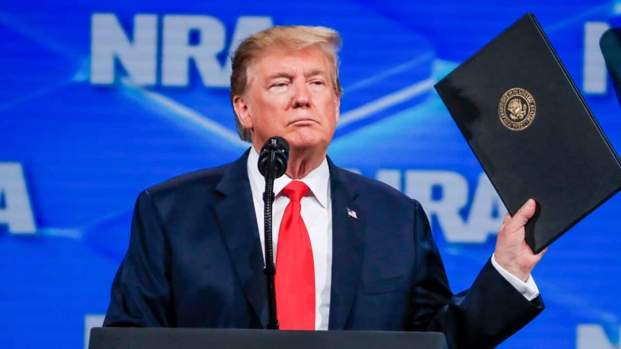 US President Donald J. Trump holds up an order he will sign withdrawing from the Arms Trade Treaty