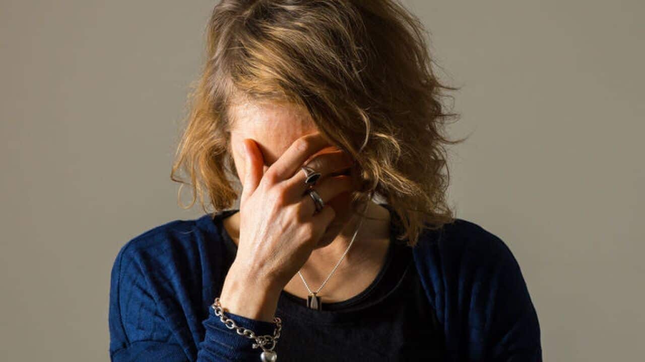 An unidentified woman with her head in her hand