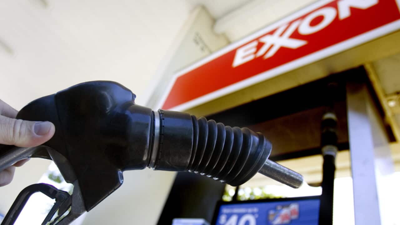 A customer holds a gas pump handle at an Exxon fuel station