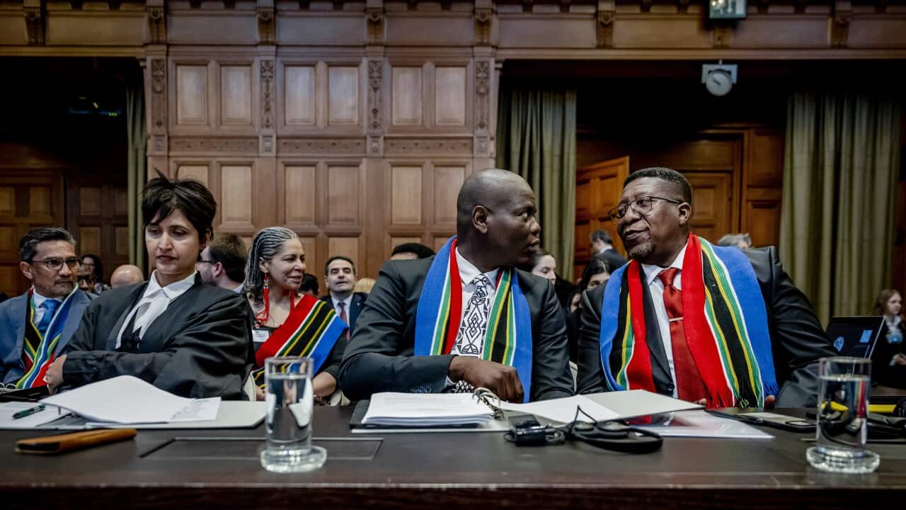 Two men and a woman seated at a desk.