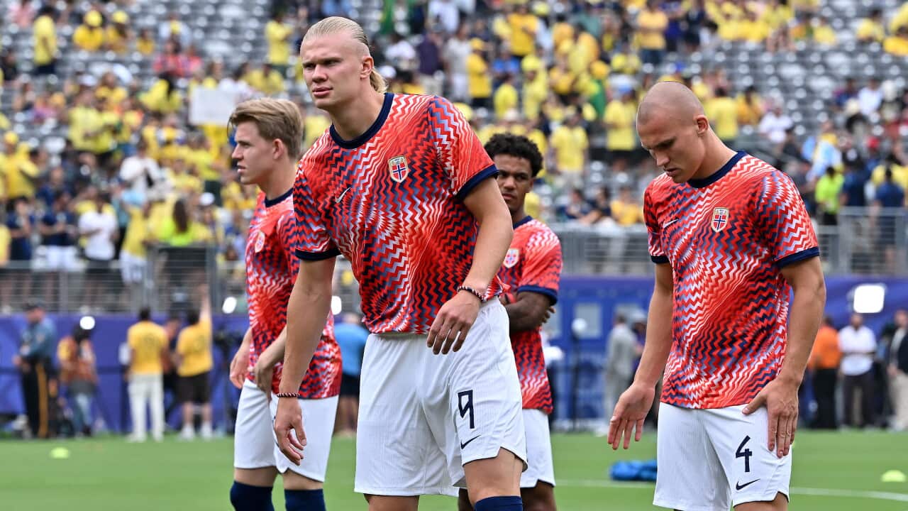 Football players in red and white shirts standing on a football pitch