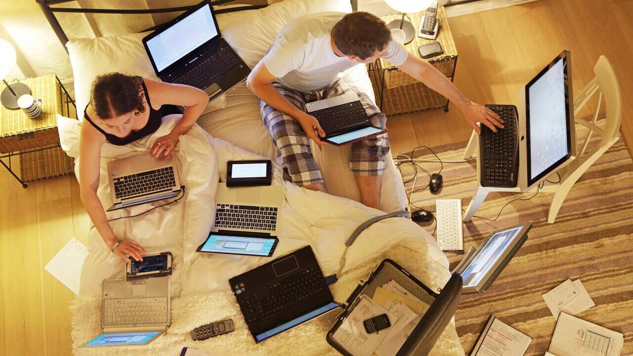Couple in bed surrounded by computers