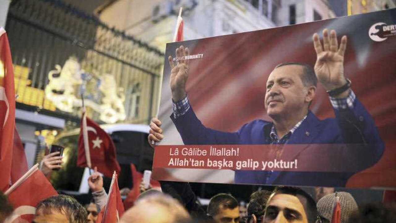 Supporters of Turkey's President Recep Tayyip Erdogan, pictured in the poster, wave flags outside the Dutch consulate during a protest, in Istanbul
