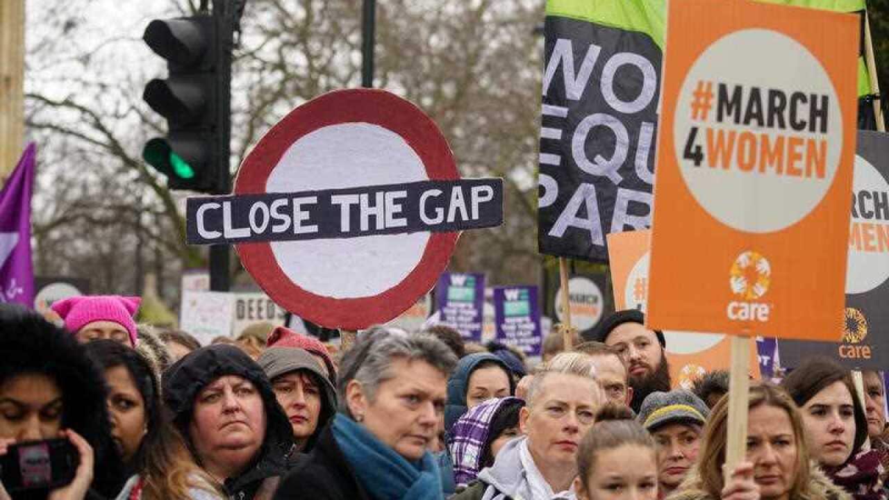 Protesters hold signs reading "Close the gap" as thousands take part in the March for Women on March 4, 2018 in London.