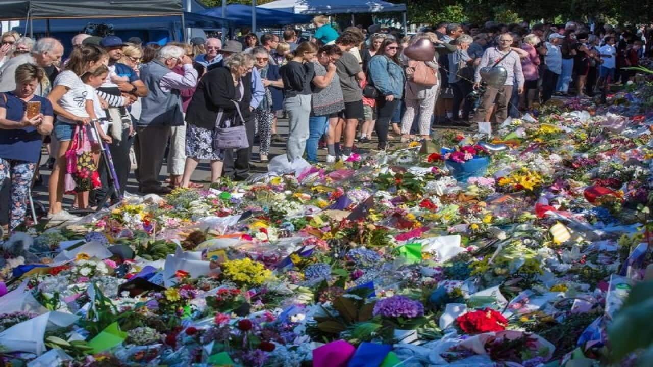 Members of the public look at a makeshift memorial
