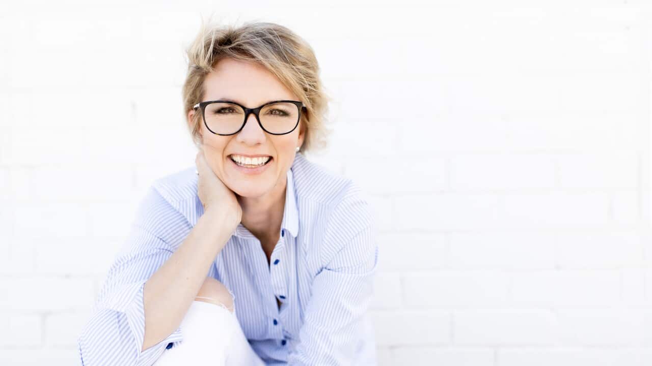 Kate sitting in front a white wall smiling.