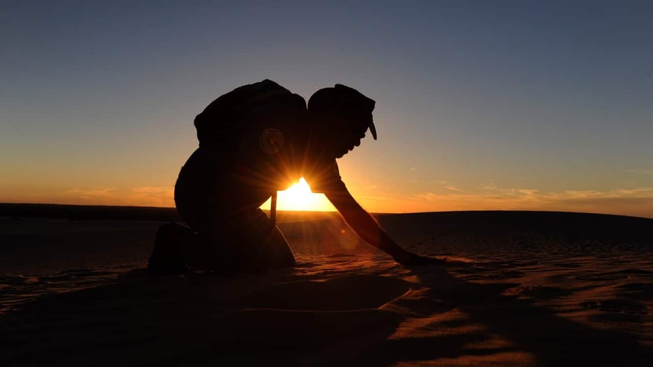 Aboriginal guide Graham Clark, set against the setting sun at the Great Walls of China in Mungo National Park.