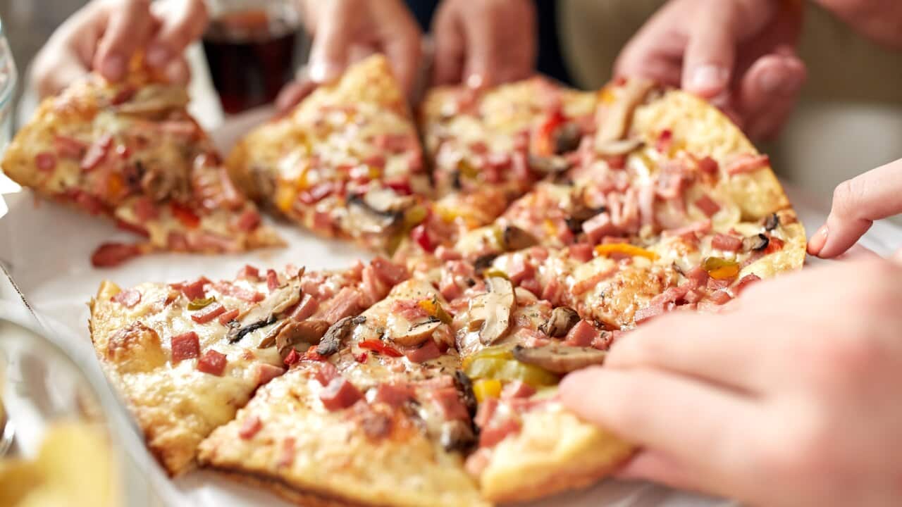 close up of hands taking pizza slices
