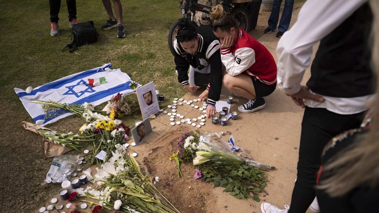 People gather and lay flowers at the site where Alessandro Parini, an Italian tourist, was killed in a Palestinian attack, in Tel Aviv, Israel, Saturday, April 8, 2023