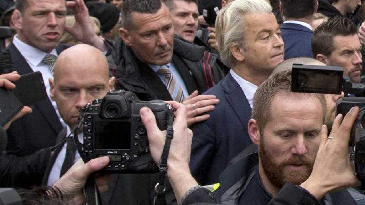 Geert Wilders, right, is protected by police and security officers during an election campaign