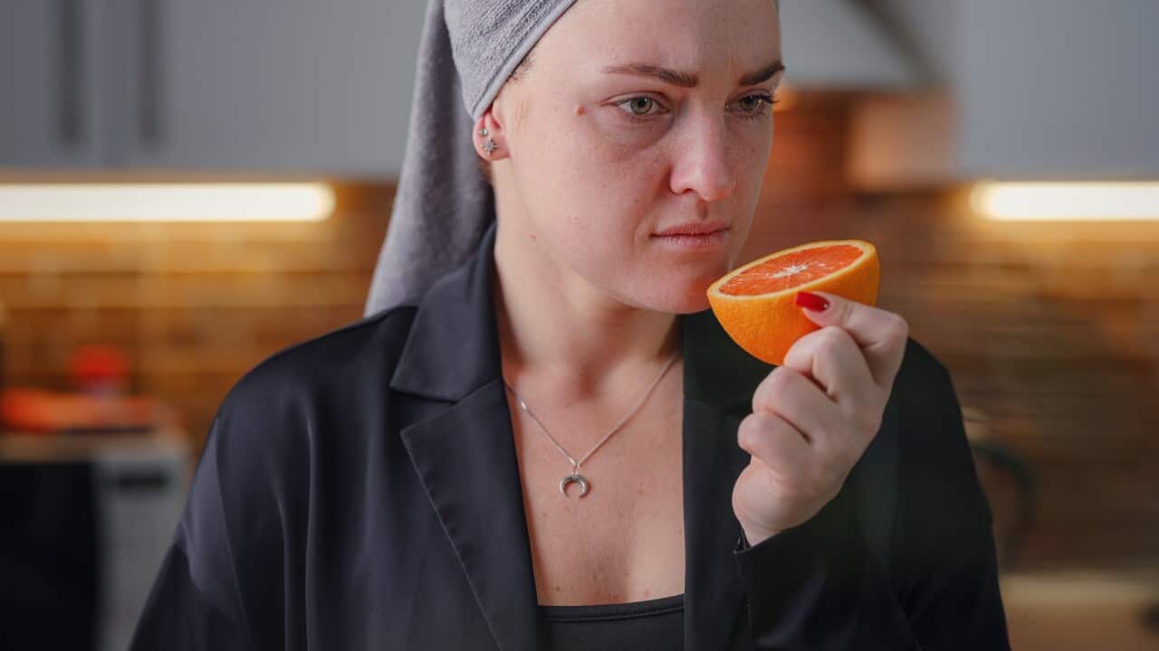 Sick woman trying to sense smell of fresh orange