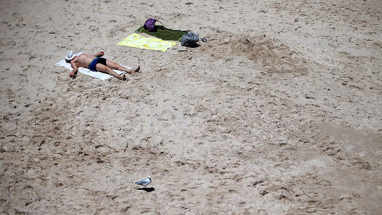 A man sunabathes in the midday sun during a heat wave at Glenelg beach on January 13, 2014.