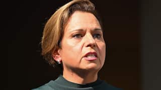 A close up shot of a woman with brown hair and a dark green jumper