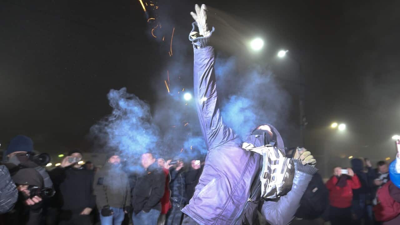 A protester throws a smoke grenade during a rally in front of the embassy of the Russian embassy in Kiev.